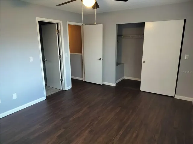 an empty room with wooden floor and a ceiling fan