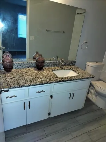 a bathroom with a granite countertop sink and a mirror