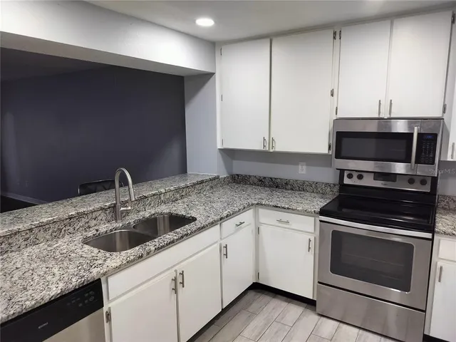 a kitchen with granite countertop white cabinets and stainless steel appliances