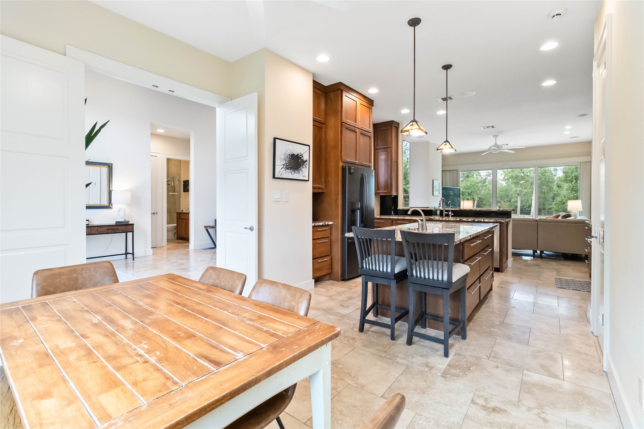 129 Powder Horn Road Bastrop, TX 78602 - Photo 27 of 27 Kitchen featuring a breakfast bar area, open floor plan, light stone counters, hanging light fixtures, and brown cabinets