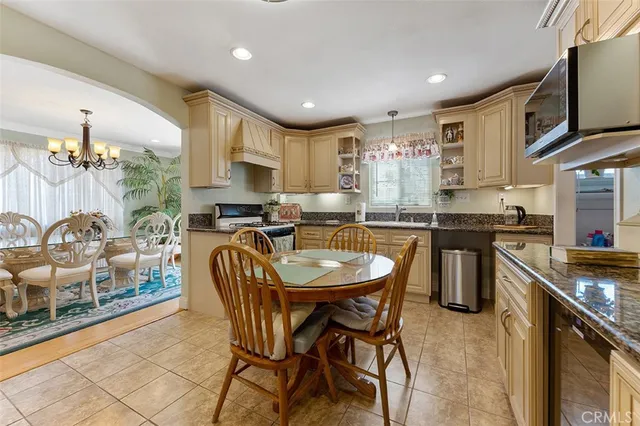 a kitchen with stainless steel appliances granite countertop a stove top oven a sink a dining table and chairs with wooden floor