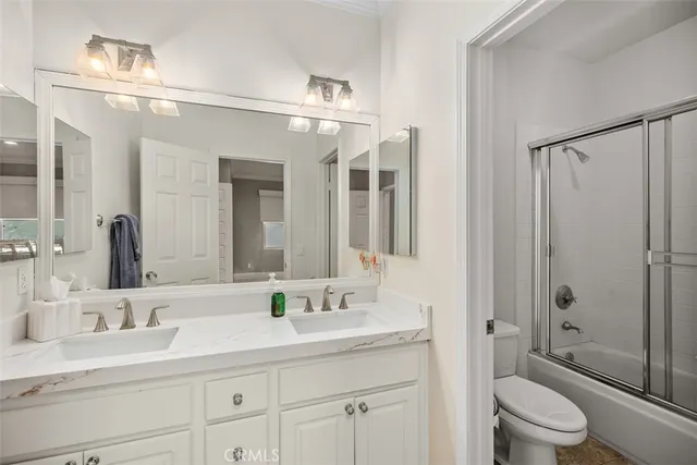 a bathroom with a granite countertop sink a toilet a mirror and shower