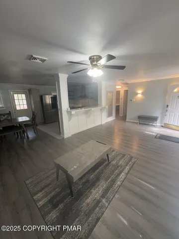 a view of a hallway with wooden floor and a kitchen