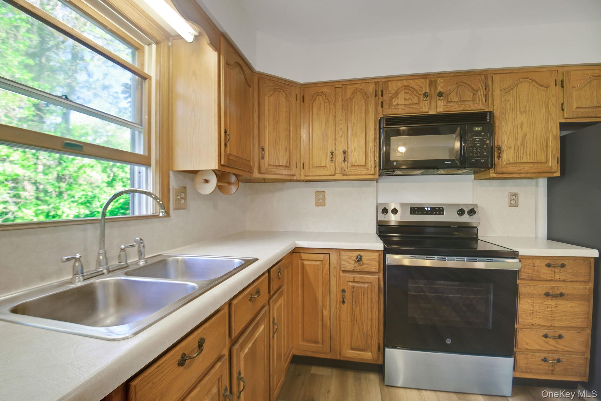 175 Overocker Road Poughkeepsie, NY 12603 - Photo 12 of 29 Kitchen featuring wood cabinetry, laminate countertops, a stainless steel double basin sink, a modern black and stainless steel range, and an over-the-range microwave