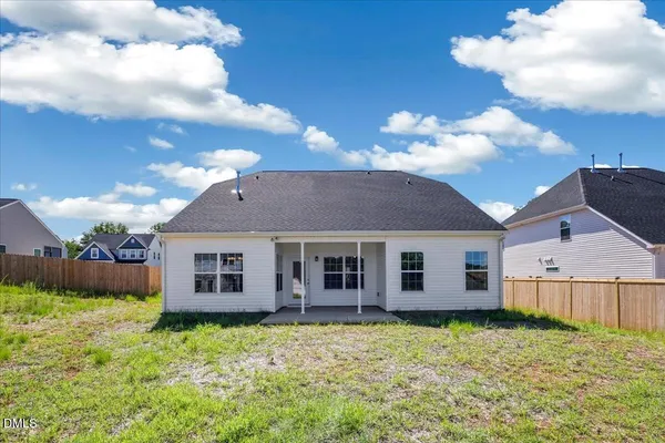 a view of a yard in front of a house with plants and large tree