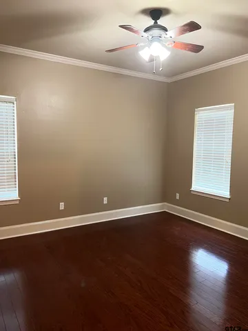 a view of an empty room with window and wooden floor