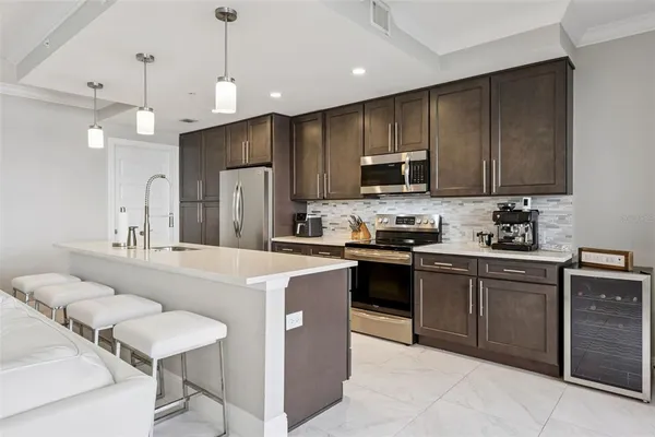 a kitchen with kitchen island a stove a sink a dining table and chairs