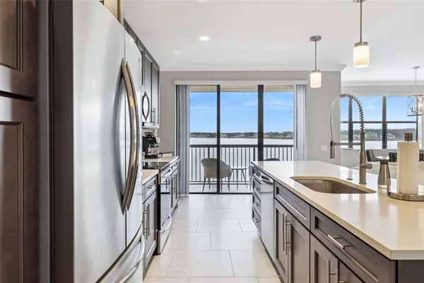 a kitchen with granite countertop a refrigerator a sink and wooden floors