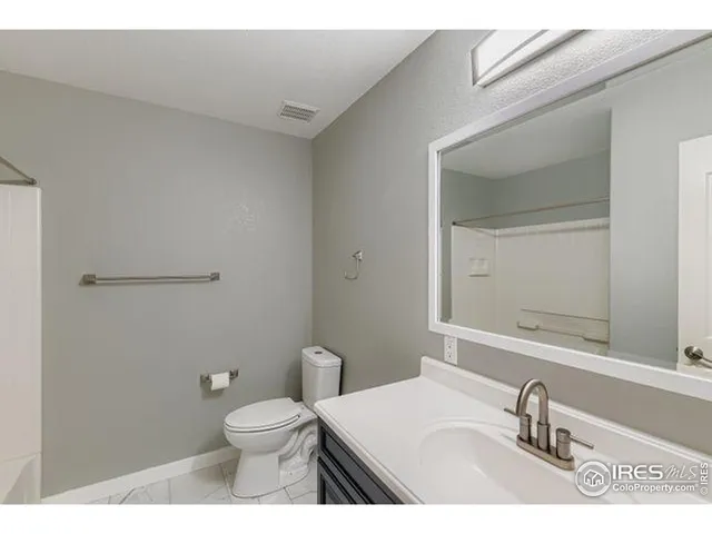 a bathroom with a granite countertop toilet a sink and a mirror