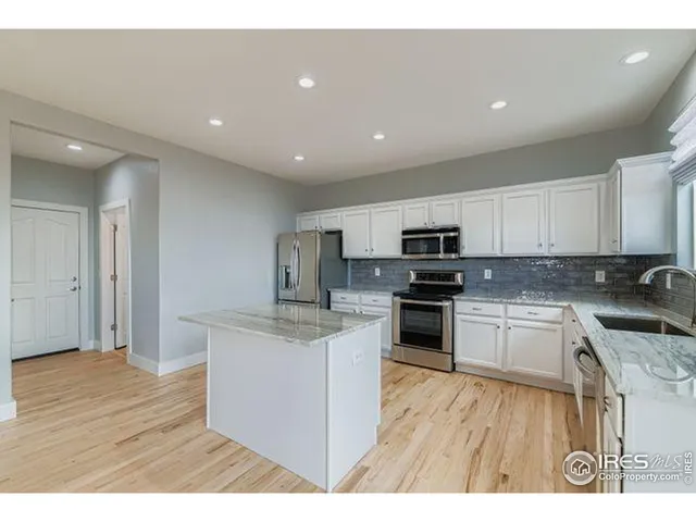 a kitchen with stainless steel appliances granite countertop a stove top oven a sink and a refrigerator