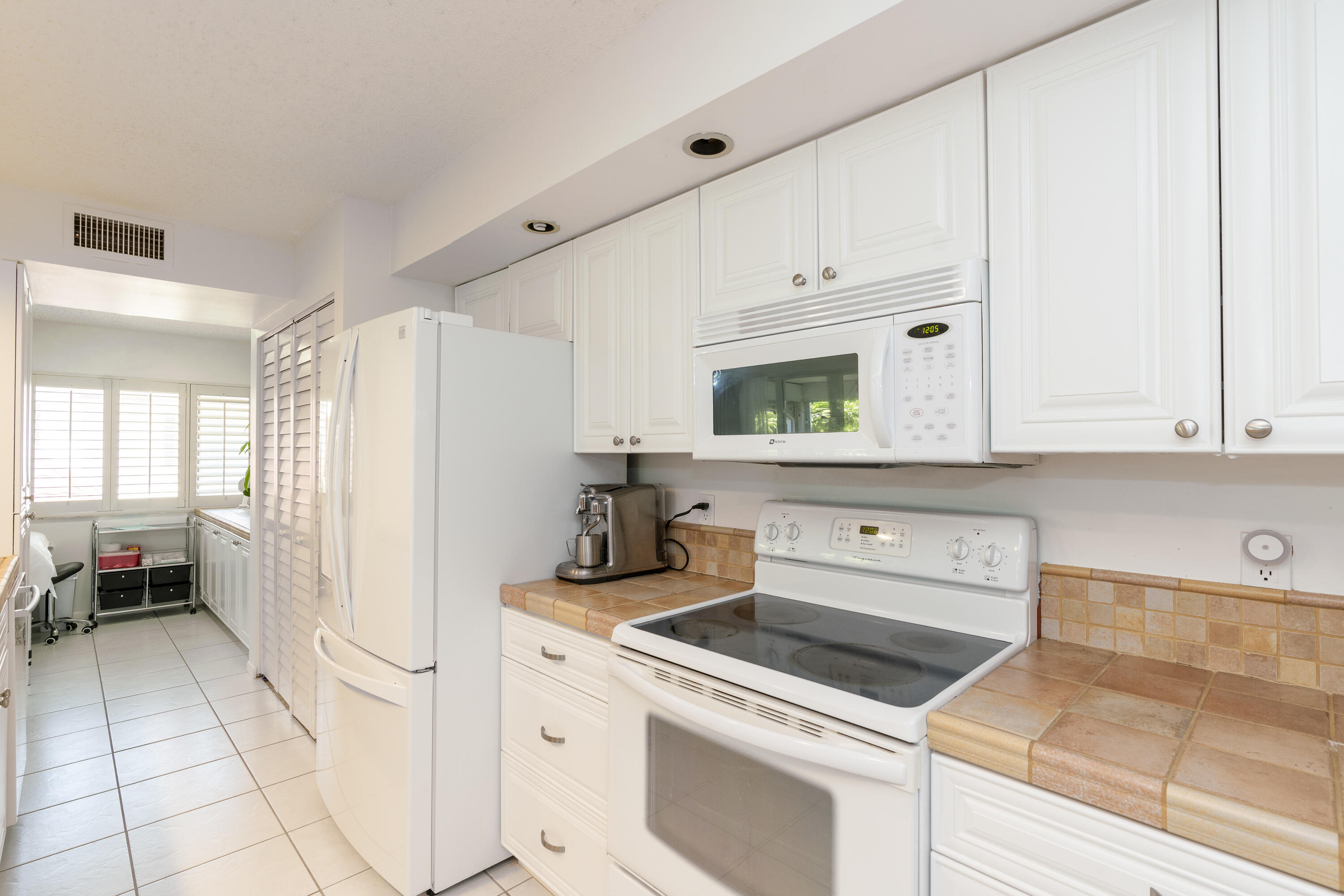 106 Half Moon Circle, Unit H2 Hypoluxo, FL 33462 - Photo 17 of 70 a kitchen with white cabinets and white appliances