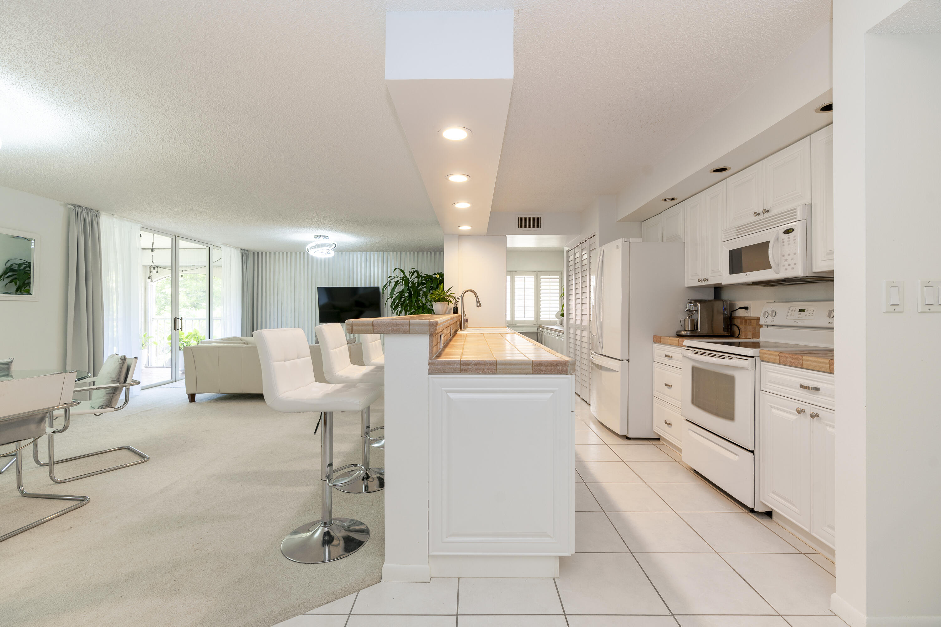 106 Half Moon Circle, Unit H2 Hypoluxo, FL 33462 - Photo 5 of 70 a kitchen with stainless steel appliances kitchen island granite countertop a stove a sink a refrigerator and white cabinets