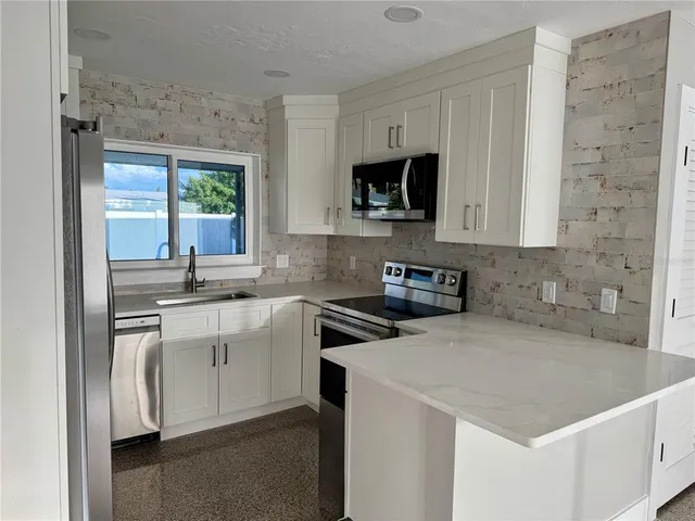 a kitchen with stainless steel appliances granite countertop a sink stove and microwave