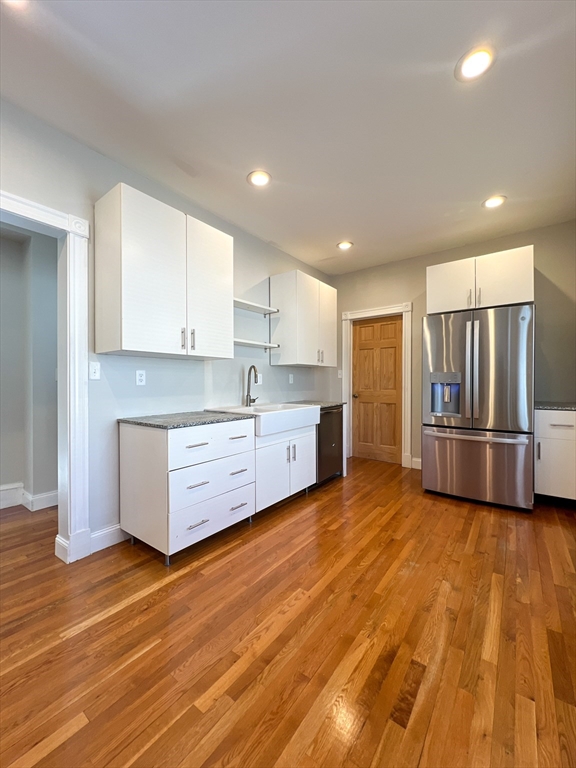 a kitchen with stainless steel appliances wooden floor and a refrigerator