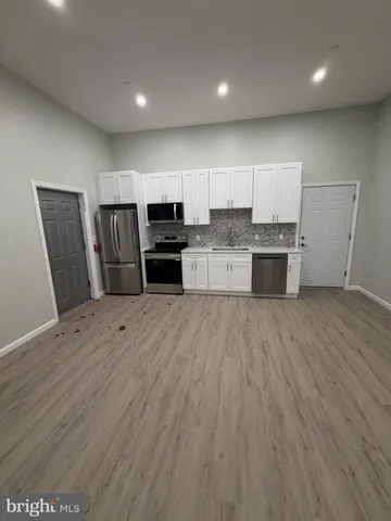 a large kitchen with stainless steel appliances wooden floors and wooden cabinets