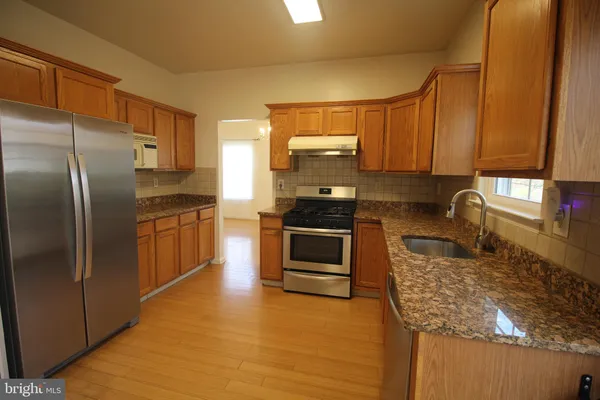 a kitchen with granite countertop a stove a sink and a refrigerator