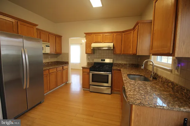 a kitchen with granite countertop a stove a sink and a refrigerator
