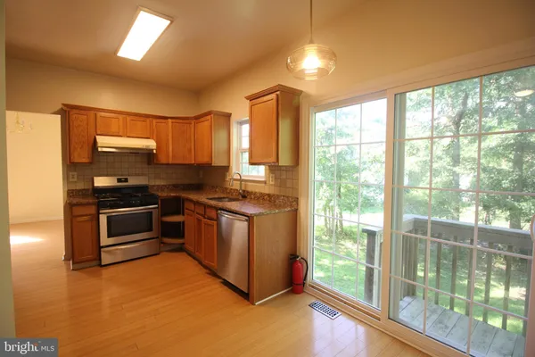 a kitchen with stainless steel appliances granite countertop a stove a sink and a microwave