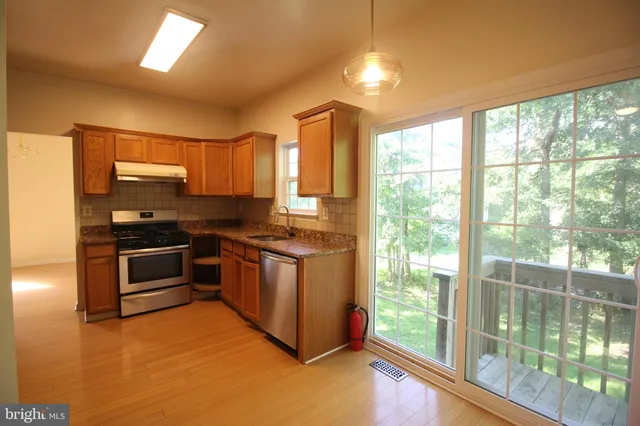 a kitchen with stainless steel appliances granite countertop a stove a sink and a microwave