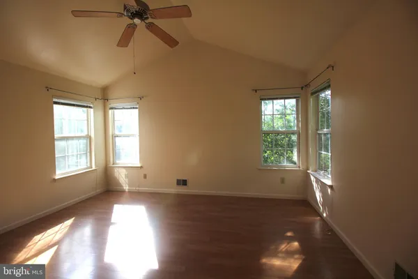 a view of empty room with wooden floor and fan