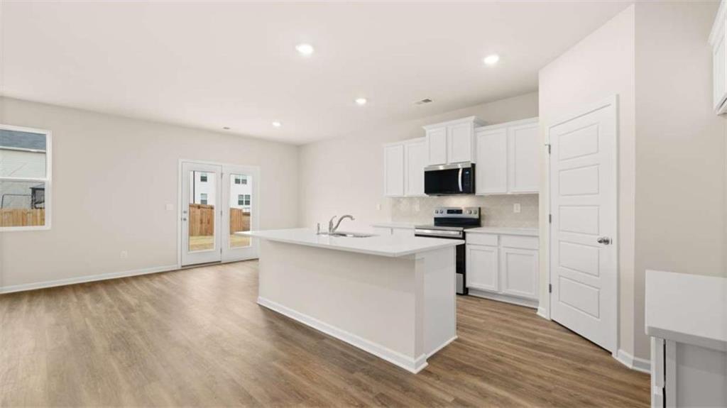202 Cattle Drive Perry, GA 31069 - Photo 8 of 30 a kitchen with stainless steel appliances granite countertop a stove top oven a sink a refrigerator and white cabinets with wooden floor