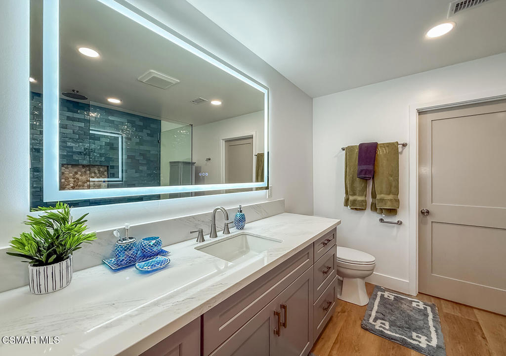 5040 Dolphin Way Oxnard, CA 93035 - Photo 14 of 26 a bathroom with a granite countertop sink a large mirror a toilet and a shower