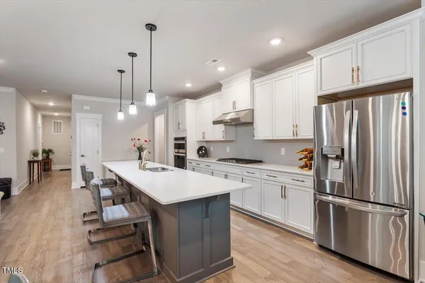 a kitchen with a refrigerator a sink and white cabinets