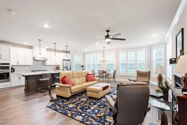 a living room with furniture kitchen view and a large window