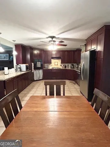 a large kitchen with stainless steel appliances kitchen island granite countertop a refrigerator a stove a sink dishwasher with a dining table and chair