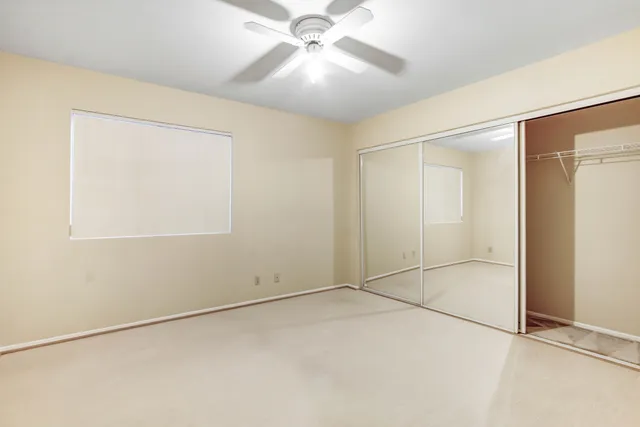 an empty room with a ceiling fan and a window