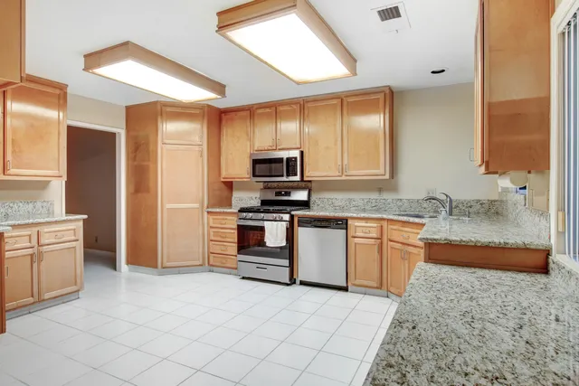 a kitchen with granite countertop a stove a sink and a refrigerator