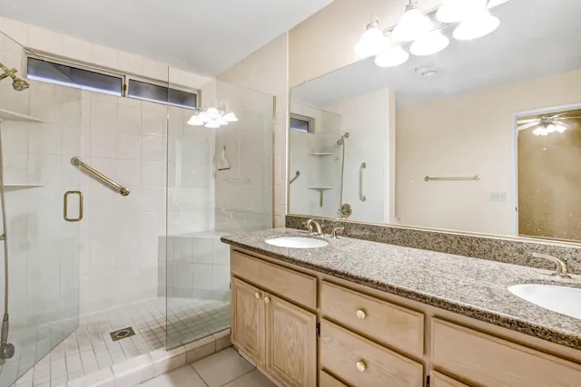a bathroom with a granite countertop sink a mirror and shower