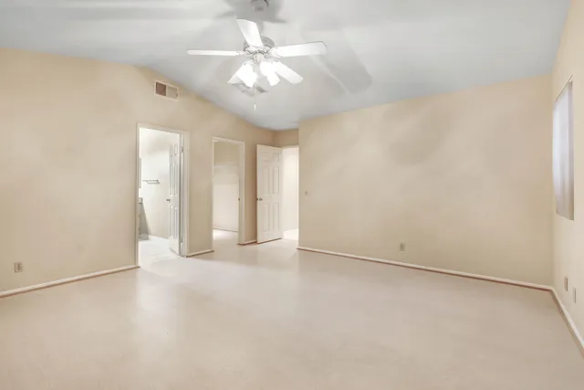 an empty room with a chandelier fan and windows