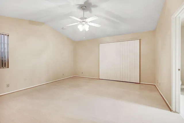 an empty room with a chandelier fan and windows