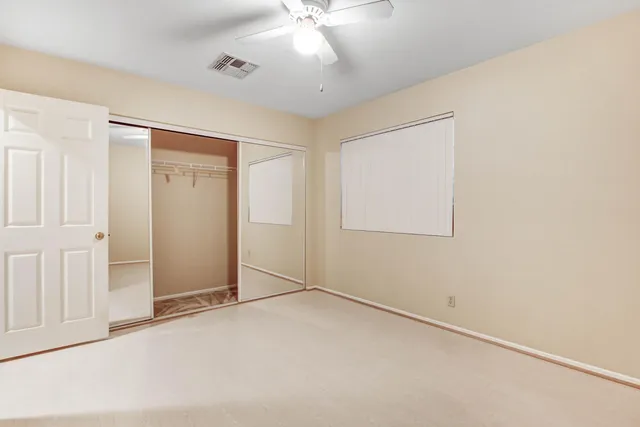 an empty room with a ceiling fan and a window