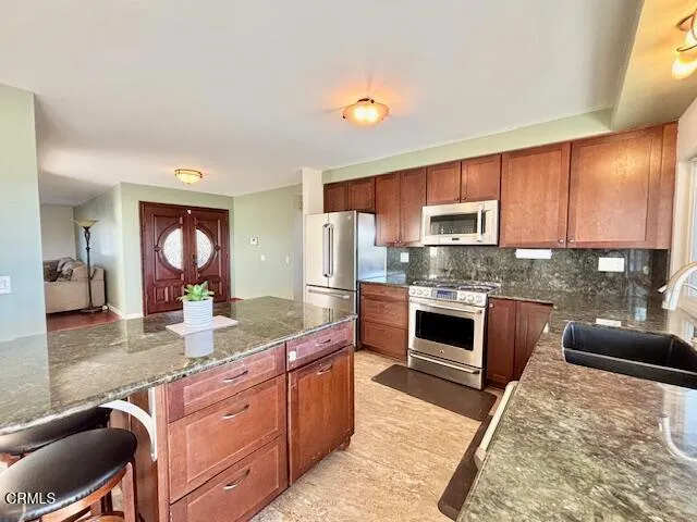 a large kitchen with granite countertop a stove refrigerator and a sink