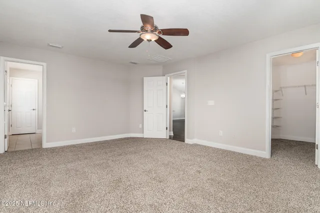 an empty room with closet and a ceiling fan