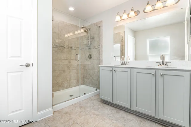 a bathroom with a double vanity sink mirror and shower