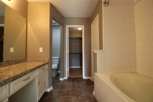 a bathroom with a granite countertop sink and a bathtub