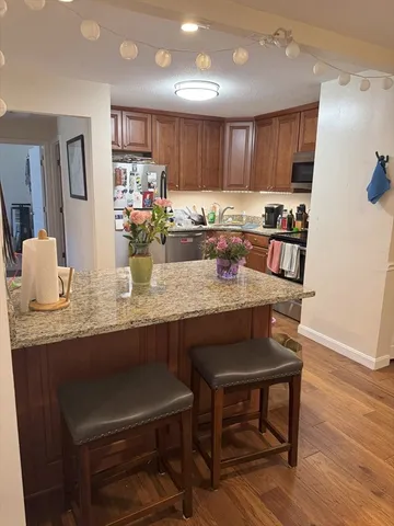 a kitchen with granite countertop a table chairs microwave and cabinets