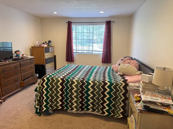 a bedroom with a bed and dresser with mirror