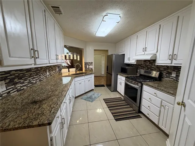 a kitchen with stainless steel appliances kitchen island granite countertop a refrigerator stove and sink