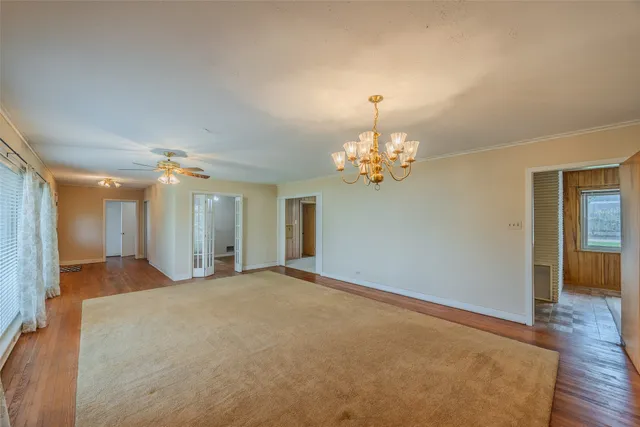 a view of a livingroom with a chandelier fan and windows