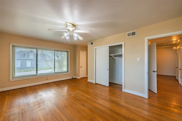 a view of an empty room with a window and wooden floor