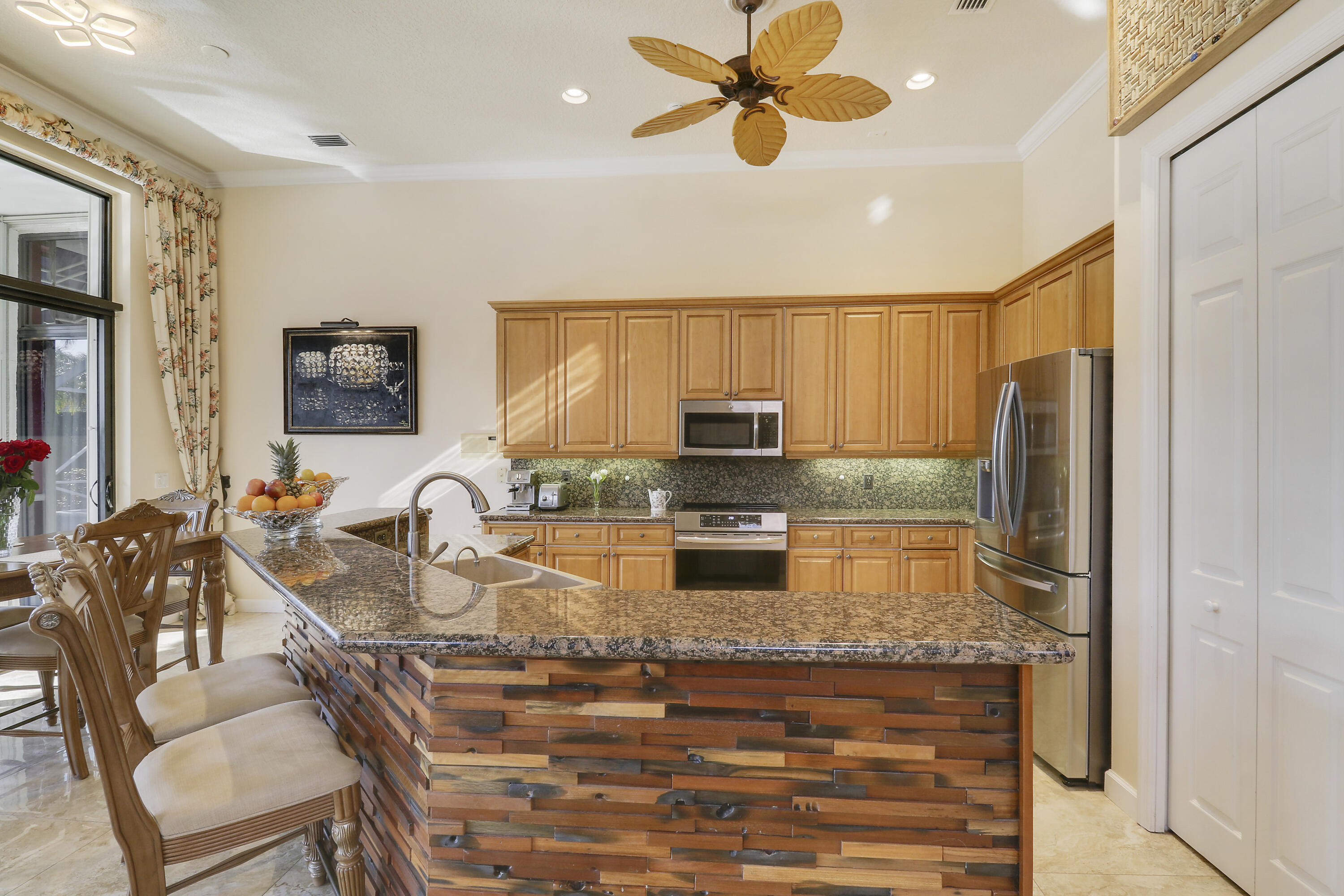 8216 Cypress Point Road West Palm Beach, FL 33412 - Photo 27 of 62 a kitchen with stainless steel appliances granite countertop a stove top oven a sink a dining table and chairs with wooden floor
