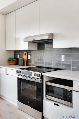 a kitchen with granite countertop a sink a stove and cabinets