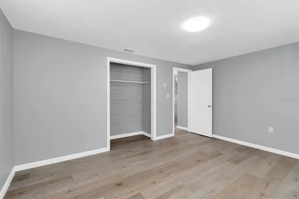a view of an empty room with wooden floor & closet