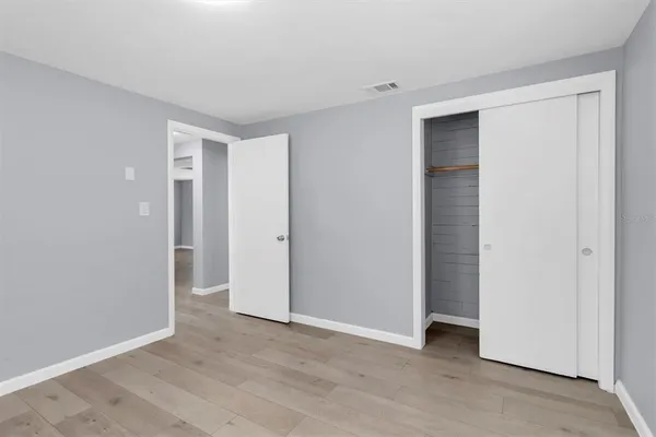 a view of an empty room with closet and wooden floor