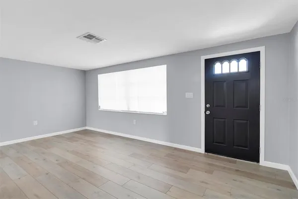 a view of an empty room with wooden floor and a window