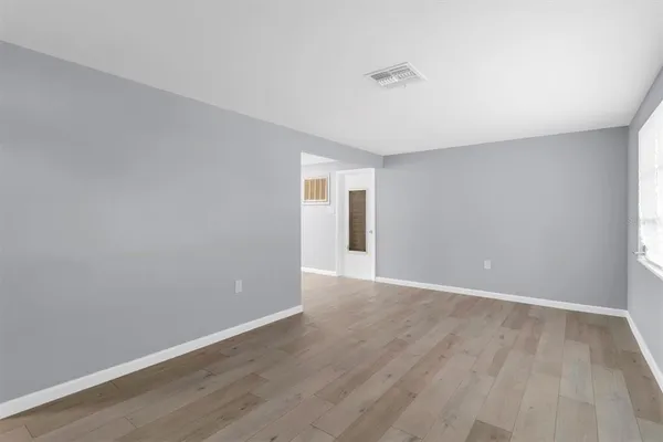 a view of an empty room with wooden floor and a window